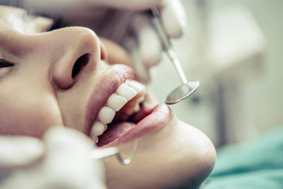 Dentist examining child's teeth during dental checkup with professional instruments.